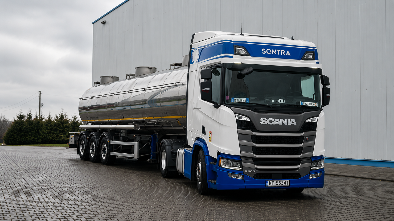 Biało-niebieska Scania SONTRA R500 przy hali
